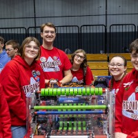 Six teammates smile around their robot